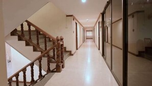 A hallway with a wooden staircase on the left and a glass door on the right. - Hua Lin Inn (Chiang Mai)