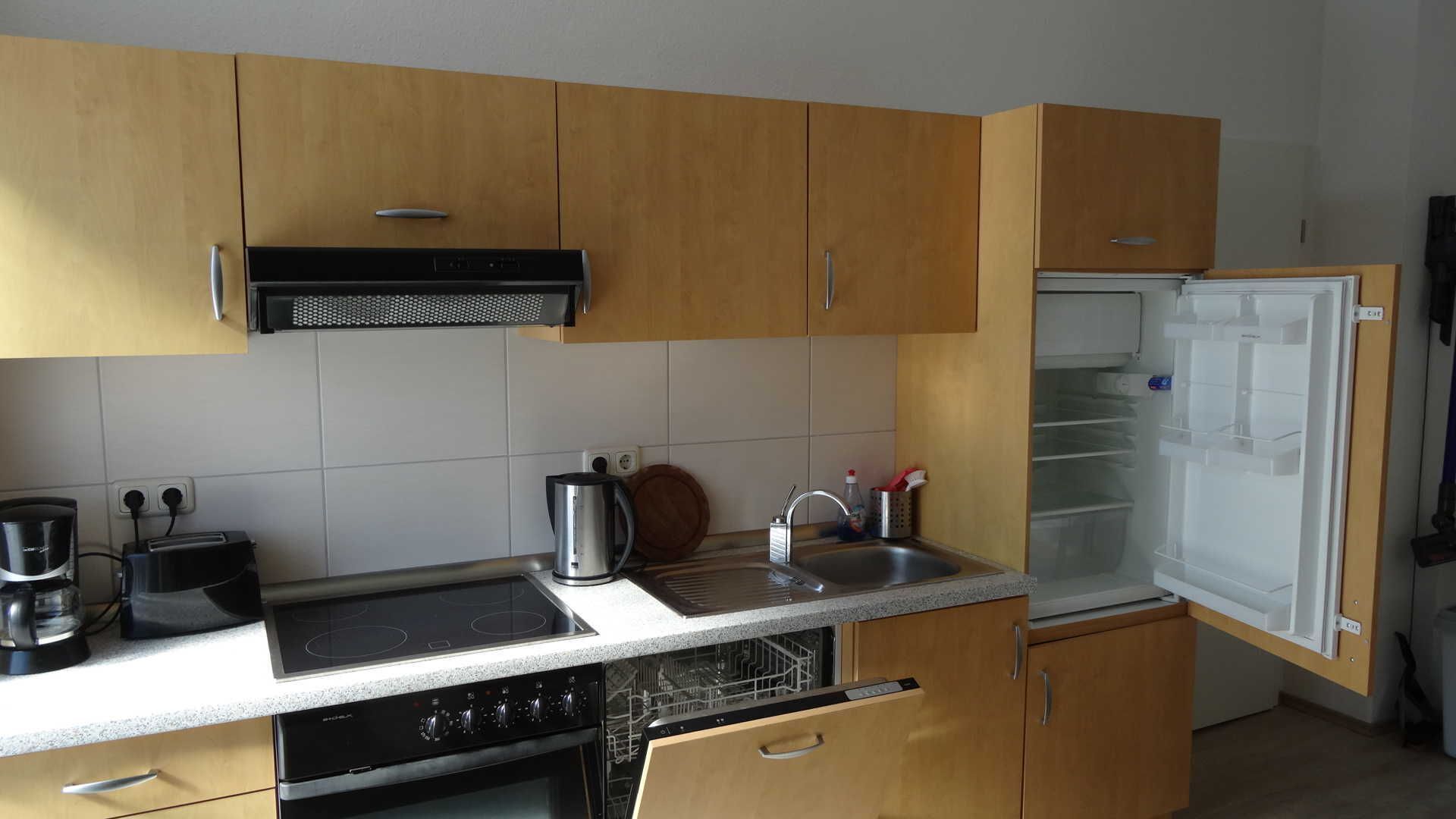 A kitchen with wooden cabinets, a built-in stove, a dishwasher, and a refrigerator.