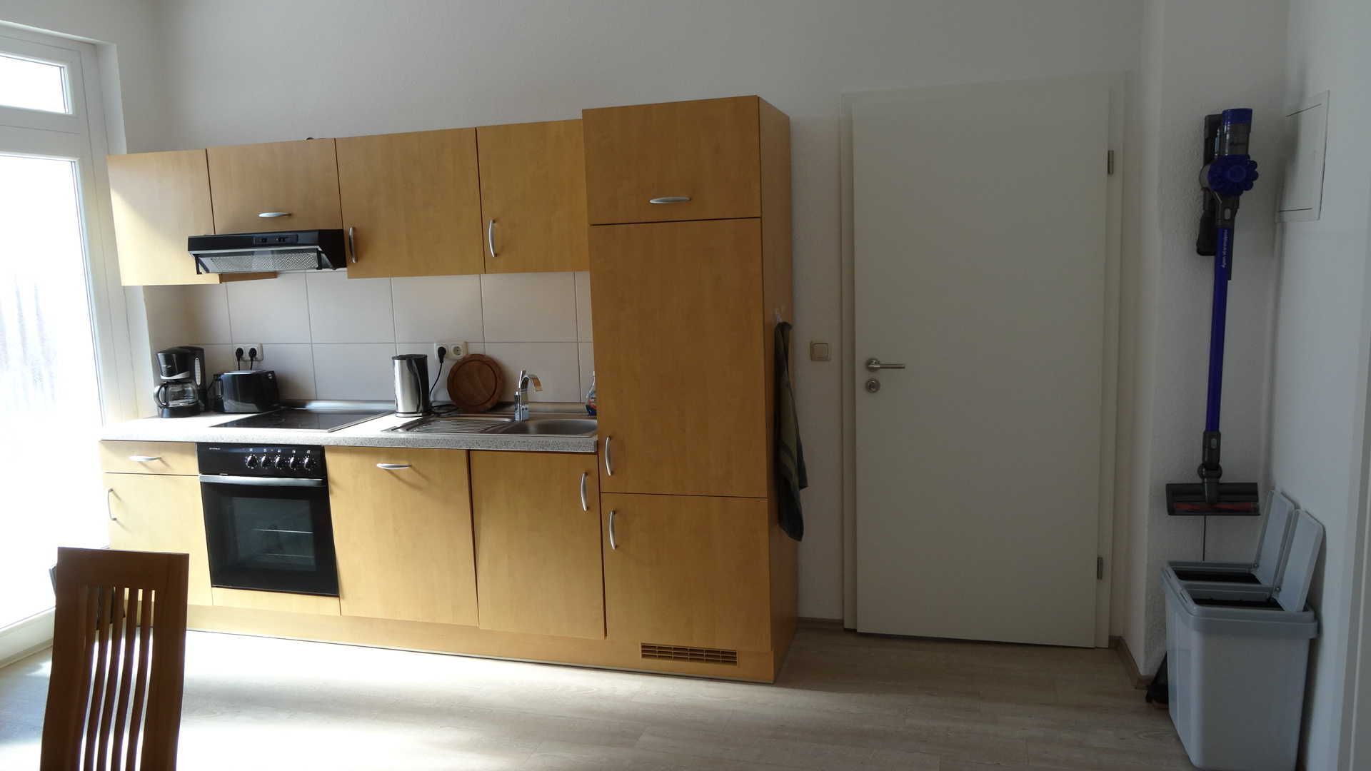 A compact kitchen with wooden cabinets, a built-in oven, and a coffee maker.