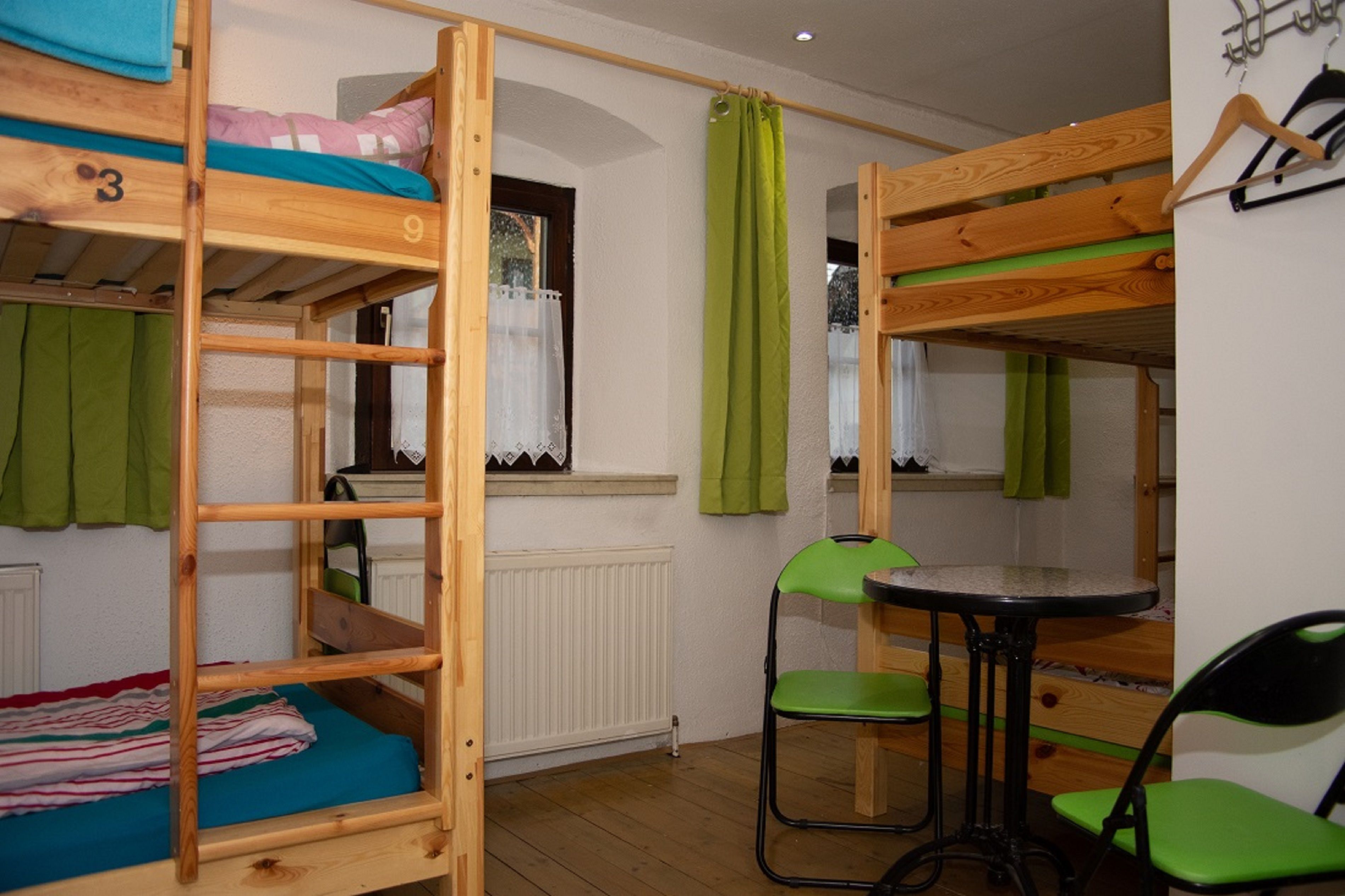 A dormitory room with bunk beds, a small table, and chairs.