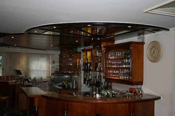 Eine Bar mit Holzausstattung, darunter Schränke, Regale und eine Wanduhr.