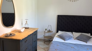 A bedroom with a bed, dresser, mirror, and decorative wall piece.