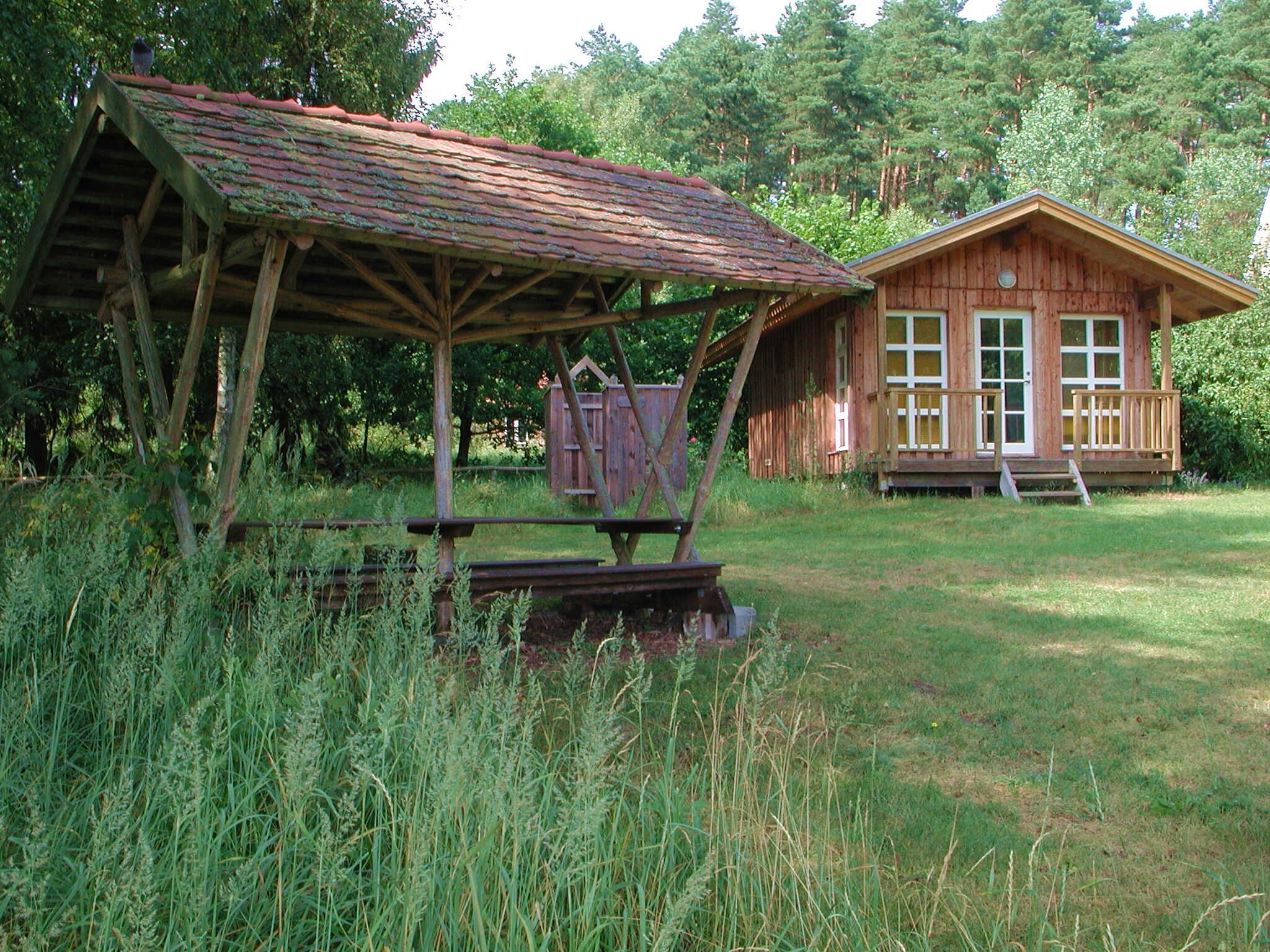 A rustic wooden cabin with a porch and a covered outdoor seating area.
