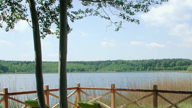 A wooden deck with chairs and a view of a lake.