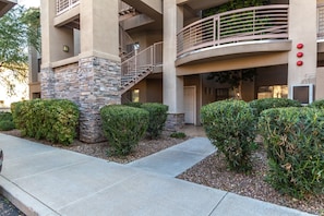 A multi-story building with a stone facade, a curved balcony, and a gated entrance.