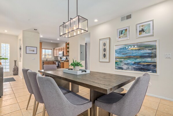 A dining area with a wooden table, grey upholstered chairs, and a pendant light.