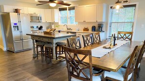 A spacious kitchen with a central island, wooden chairs, and a dining table. - Lakefront Lookout- Hot tub- Fireplace- Dock- Bar/Game Room (Fort Ann)