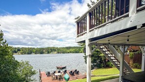 A deck with outdoor furniture overlooking a lake, a wooden staircase, and a clear sky. - Lakefront Lookout- Hot tub- Fireplace- Dock- Bar/Game Room (Fort Ann)