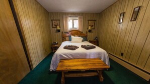 Una habitación con una cama de madera, un banco y una alfombra verde.