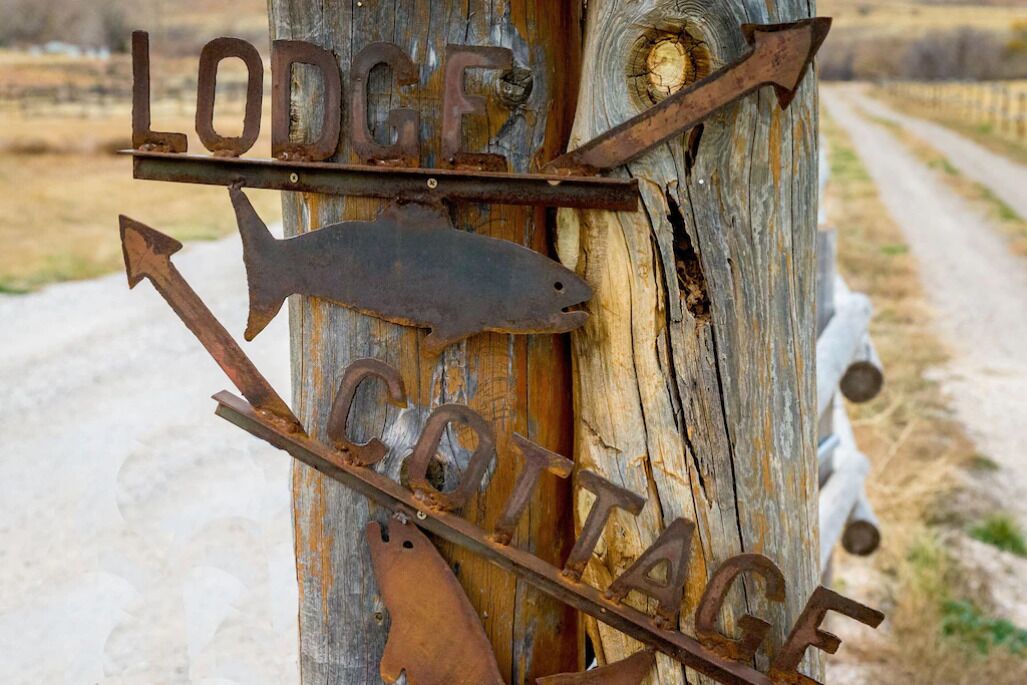A rustic wooden sign with the words "Lodge" and "Cottage" and arrows pointing in different directions.