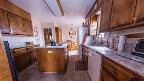 Una cocina con armarios de madera, una isla central y un comedor con mesa y sillas.