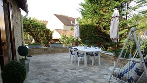 A patio with stone flooring, a white table with chairs, and a swing chair. - Very typical house LOT (Périgord-Quercy) close communal pool + Trade (Lavercantière)