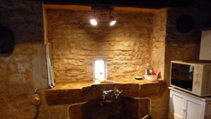 A rustic stone-walled room with a stone bench, a small window, a microwave on a cabinet, and a water dispenser on the bench. - Very typical house LOT (Périgord-Quercy) close communal pool + Trade (Lavercantière)