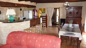 A cozy living area with a red sofa, wooden dining table, and a kitchen area with a refrigerator and a lamp. - Very typical house LOT (Périgord-Quercy) close communal pool + Trade (Lavercantière)