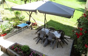 An outdoor patio with a table and chairs, a grill, and a blue table tennis table.