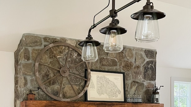 A kitchen with a stone fireplace, a wooden shelf, a large wheel, and a marble countertop. - Make lifelong memories at this New England Quintessential Country Getaway (Brookfield)
