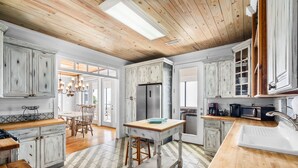 A spacious kitchen with wooden cabinets, a central island, and a large window. - Beachfront Property in Ocean Springs, Overlooking the Gulf of Mexico. Sleeps 14 (Ocean Springs)