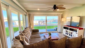 A living room with a sofa, a coffee table, and a TV stand. - Beautifully Updated Ground Floor Condo, Direct OCEAN Front on NO-DRIVE Beach! (New Smyrna Beach)