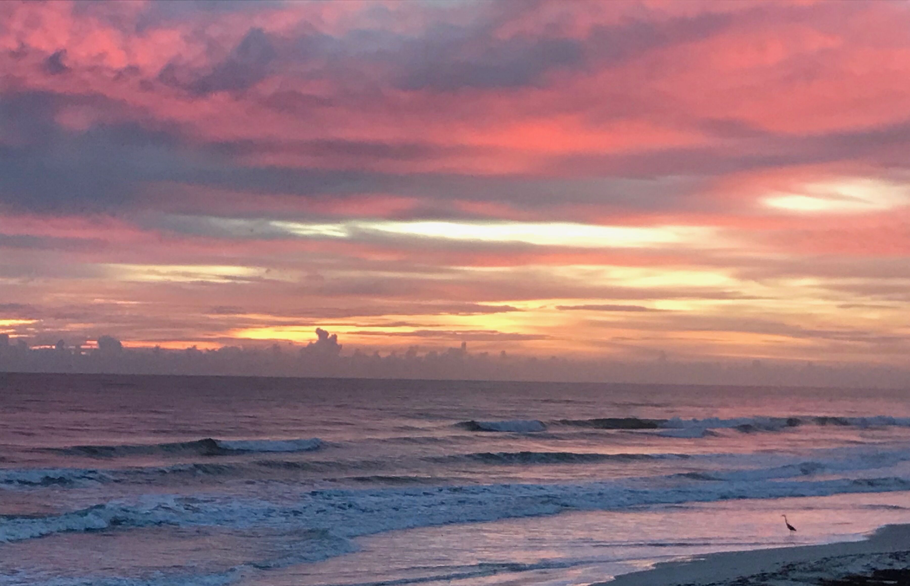 A beach with waves and a sunset.