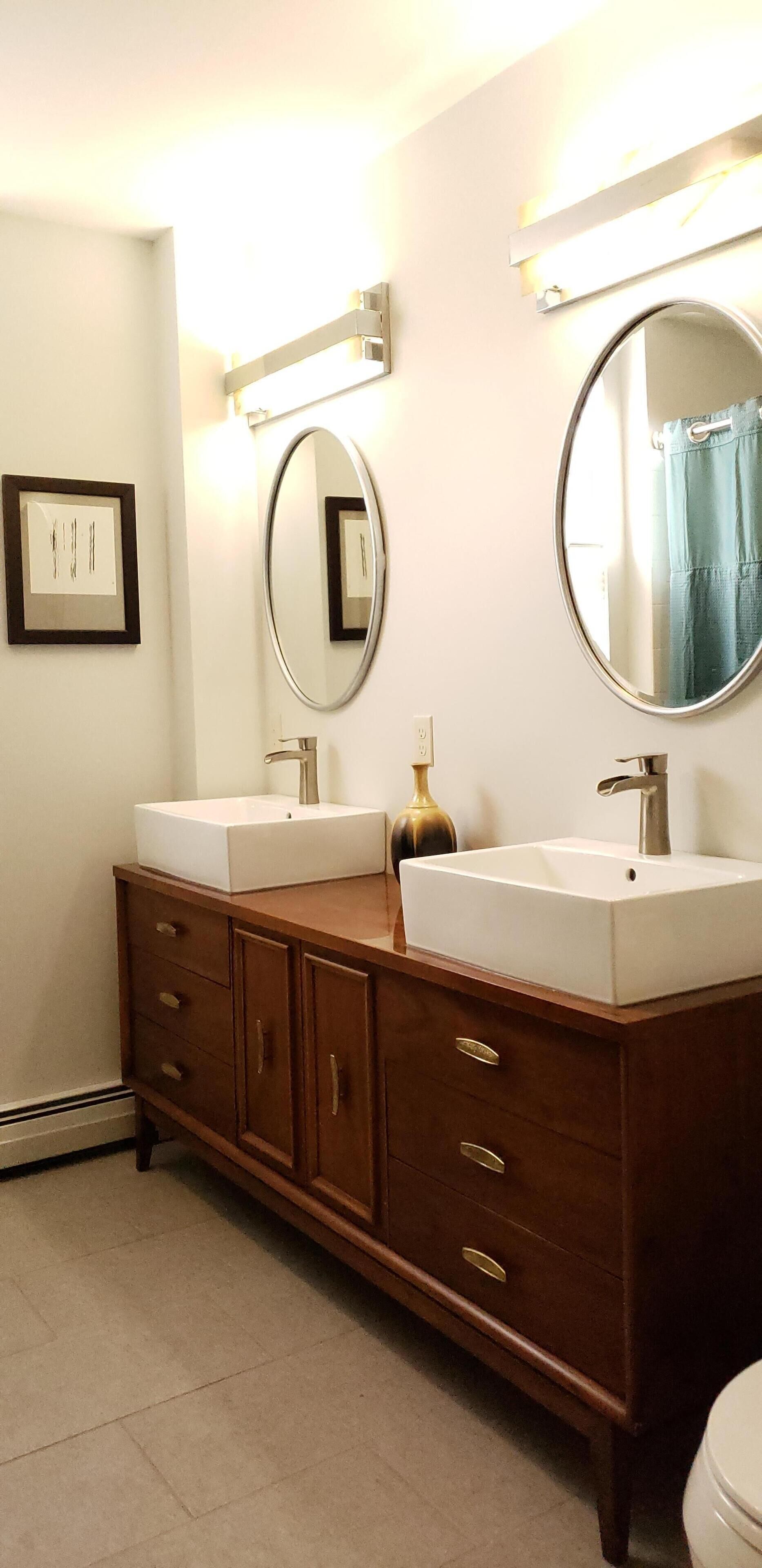 Une salle de bain avec deux lavabos, un miroir et un meuble.