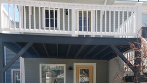 Une maison à deux étages avec un porche couvert, une porte d’entrée et un petit banc.