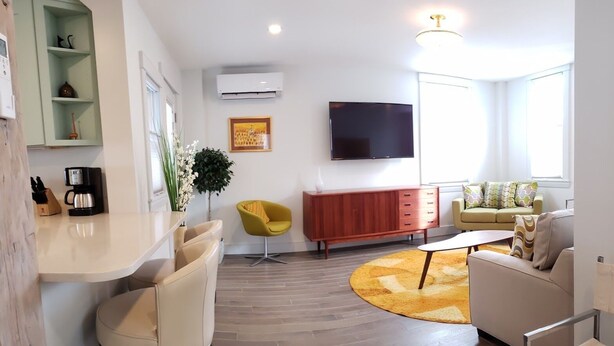 Un salon moderne avec un téléviseur à écran plat, un fauteuil jaune, un canapé beige et une table basse.