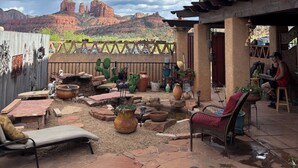 Eine Terrasse im Freien mit Steinböden, einer überdachten Sitzgruppe und Blick auf rote Felsformationen.
