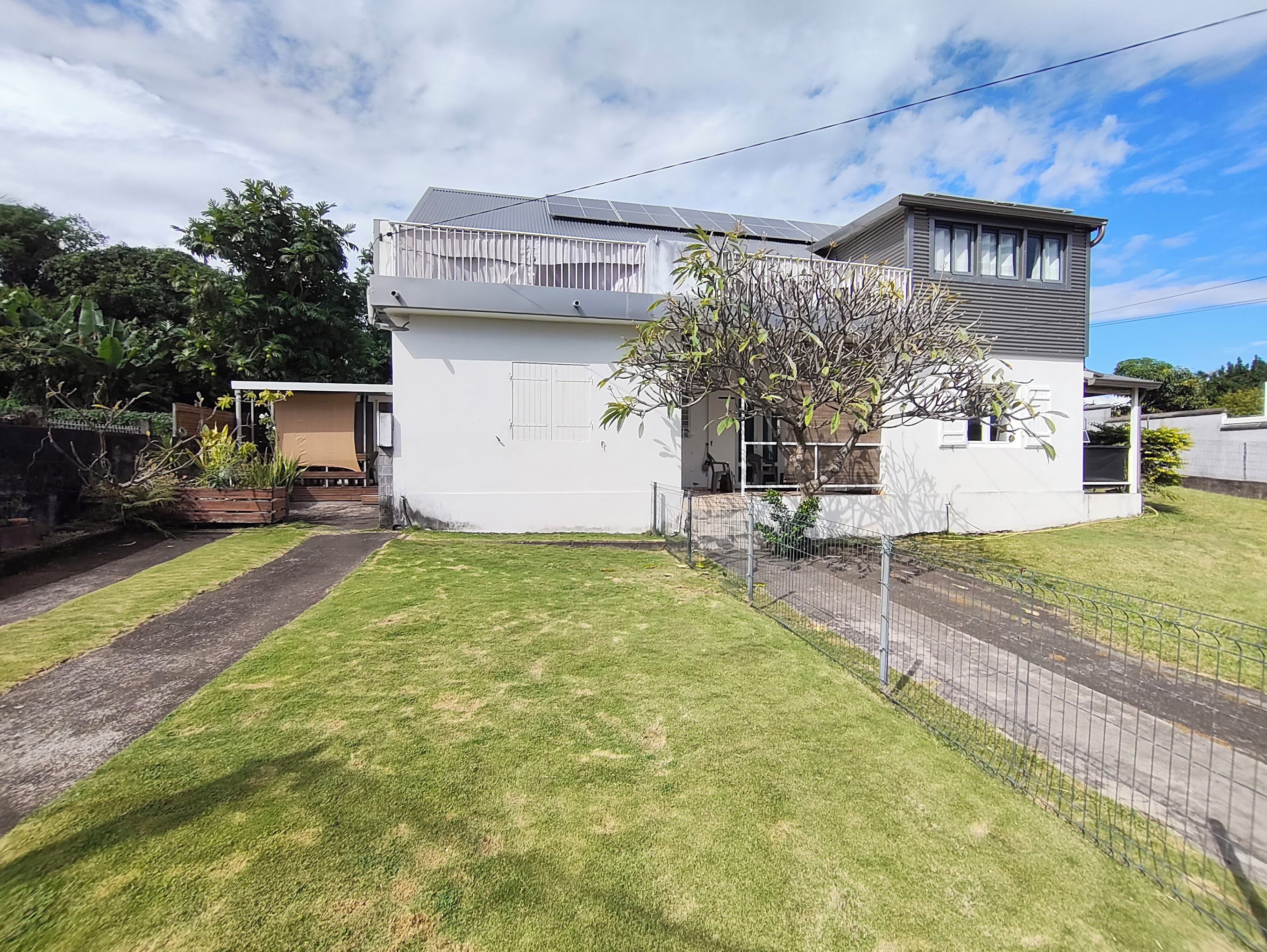 A modern two-story house with a fenced yard and a small garden area.