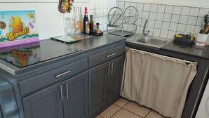 Cozinha com armários cinza escuro, pia e painel de azulejos.