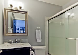 Une salle de bain avec un lavabo en marbre, des toilettes, une douche en verre et un miroir avec un cadre doré.