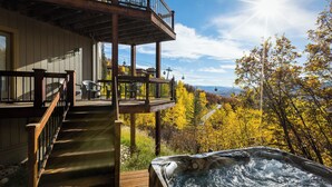 Eine Holzterrasse mit Whirlpool und Blick auf herbstliche Laubfärbung.