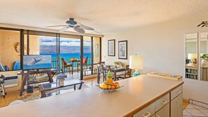 A spacious living area with a large TV, a fruit bowl, and a view of the ocean. - Great Listing/Price/AC in the bedroom! (Maalaea)