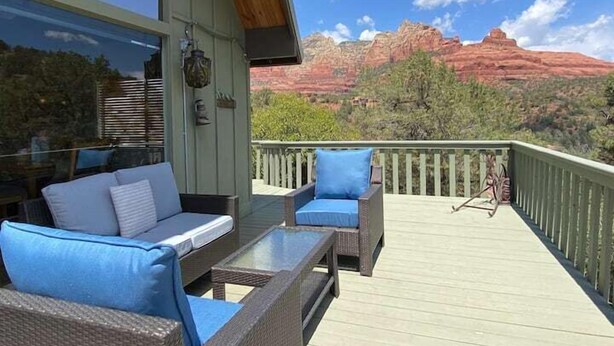A balcony with wicker furniture and a view of red rock formations. - Historic A-Frame Panoramic Red Rock Views! (Sedona)