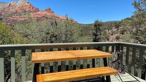 A wooden deck with a table and benches overlooking a mountainous landscape. - Historic A-Frame Panoramic Red Rock Views! (Sedona)