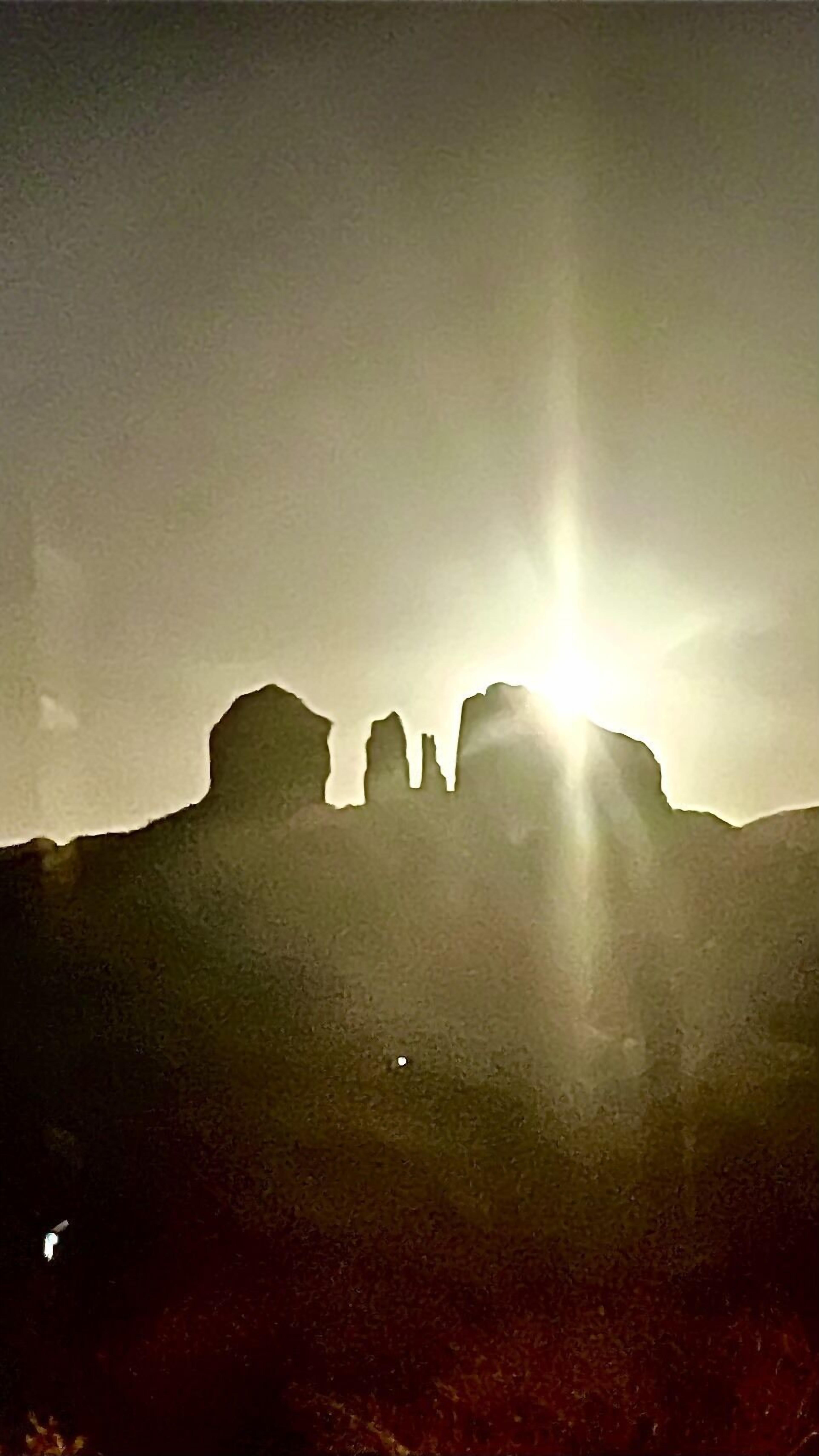 A mountain silhouette with the sun shining through.