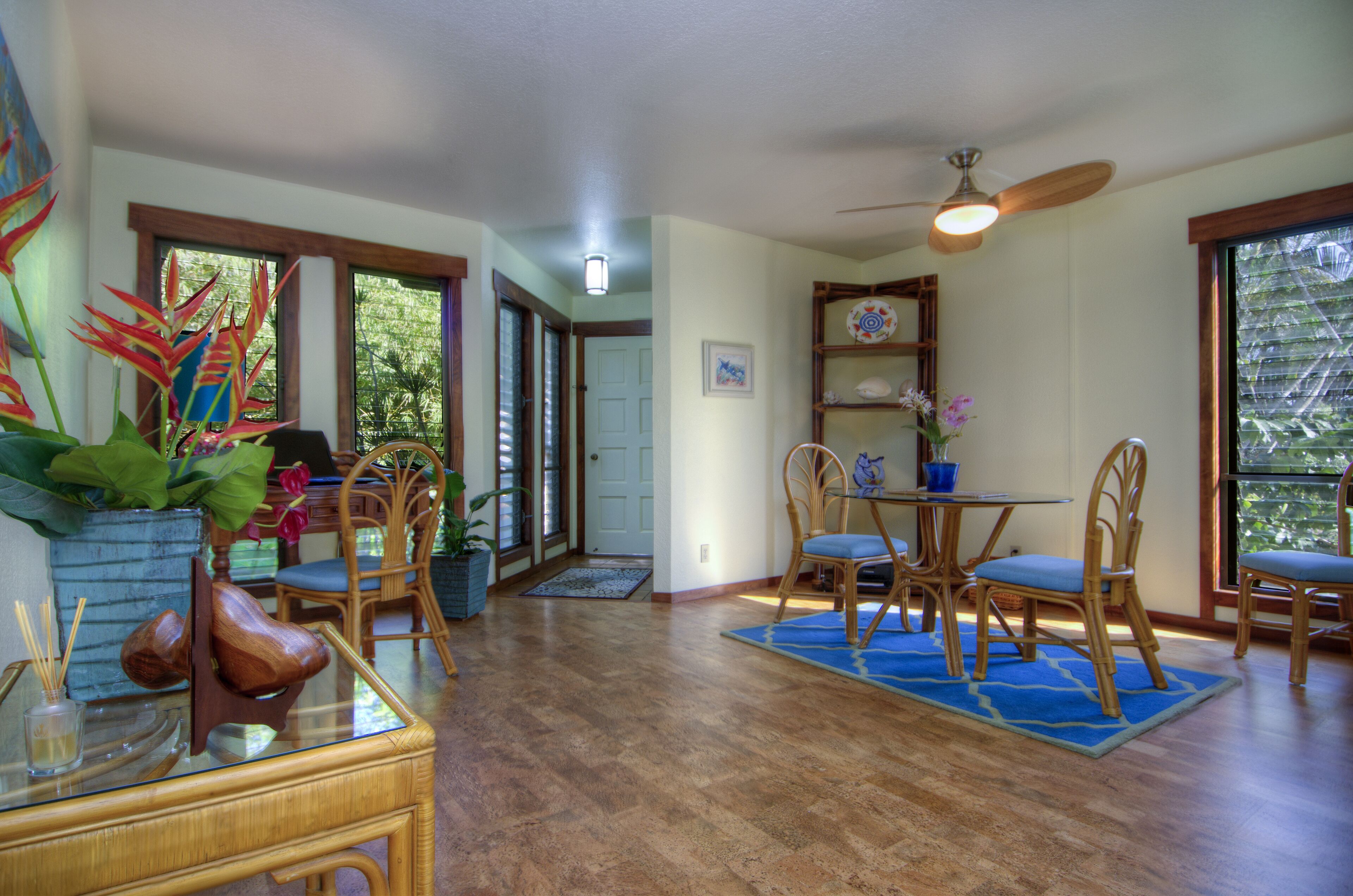 A dining area with a round table, chairs, and a ceiling fan.