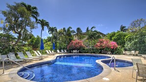Ein Poolbereich mit zwei runden Pools, Liegestühlen und Palmen.