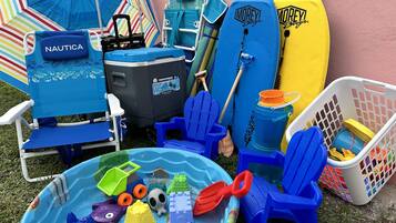 Une collection de jouets de plage, comprenant une chaise de plage bleue, une piscine gonflable bleue et divers accessoires de plage.