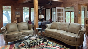 A cozy cabin interior with two leather sofas, a glass coffee table, and a colorful rug. - Bayfront Cottage. Private pier! Sunsets! Sunrises! 4 acres! New bike trail. (Gulf shores)
