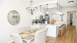 Une cuisine moderne avec des meubles blancs, un îlot central et des luminaires suspendus.