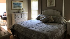 A bedroom with a large bed, a dresser, a nightstand, and a window with blinds. - Beautiful 5 bedroom, 3.5 bath home on a quiet cove on Lake Gaston (Littleton)