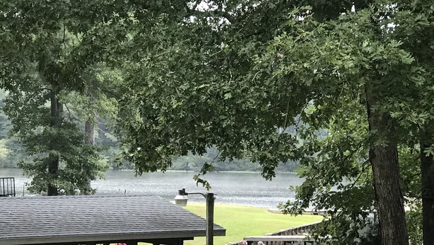 A dock with a covered seating area, a boat, and a view of a lake. - Beautiful 5 bedroom, 3.5 bath home on a quiet cove on Lake Gaston (Littleton)