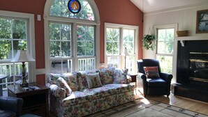 A cozy living room with a floral sofa, a black armchair, and a fireplace. - Beautiful 5 bedroom, 3.5 bath home on a quiet cove on Lake Gaston (Littleton)