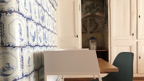 A room with a white desk, a blue chair, and a wall with blue and white patterned tiles.