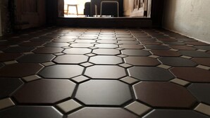 A hallway with a hexagonal tile floor leading to a bright room with a table and chairs.