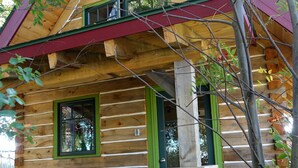 Una cabaña de troncos con terraza de madera y barandilla verde.