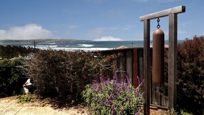 A coastal view with a wooden fence, a hanging object, and purple flowers.