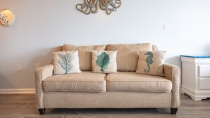 A beige sofa with three decorative pillows, a wall-mounted octopus sculpture, and a white nightstand with drawers. - The Captain and the Mermaid - Adventures in Paradise are waiting! (St Thomas)