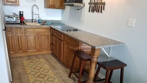 A kitchen with wooden cabinets, a granite countertop, a built-in oven, and a coffee maker. - The Captain and the Mermaid - Adventures in Paradise are waiting! (St Thomas)