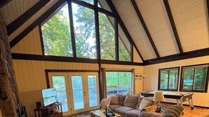 Ein geräumiges Wohnzimmer mit hoher Decke, großen Fenstern und einem gemütlichen Kamin.